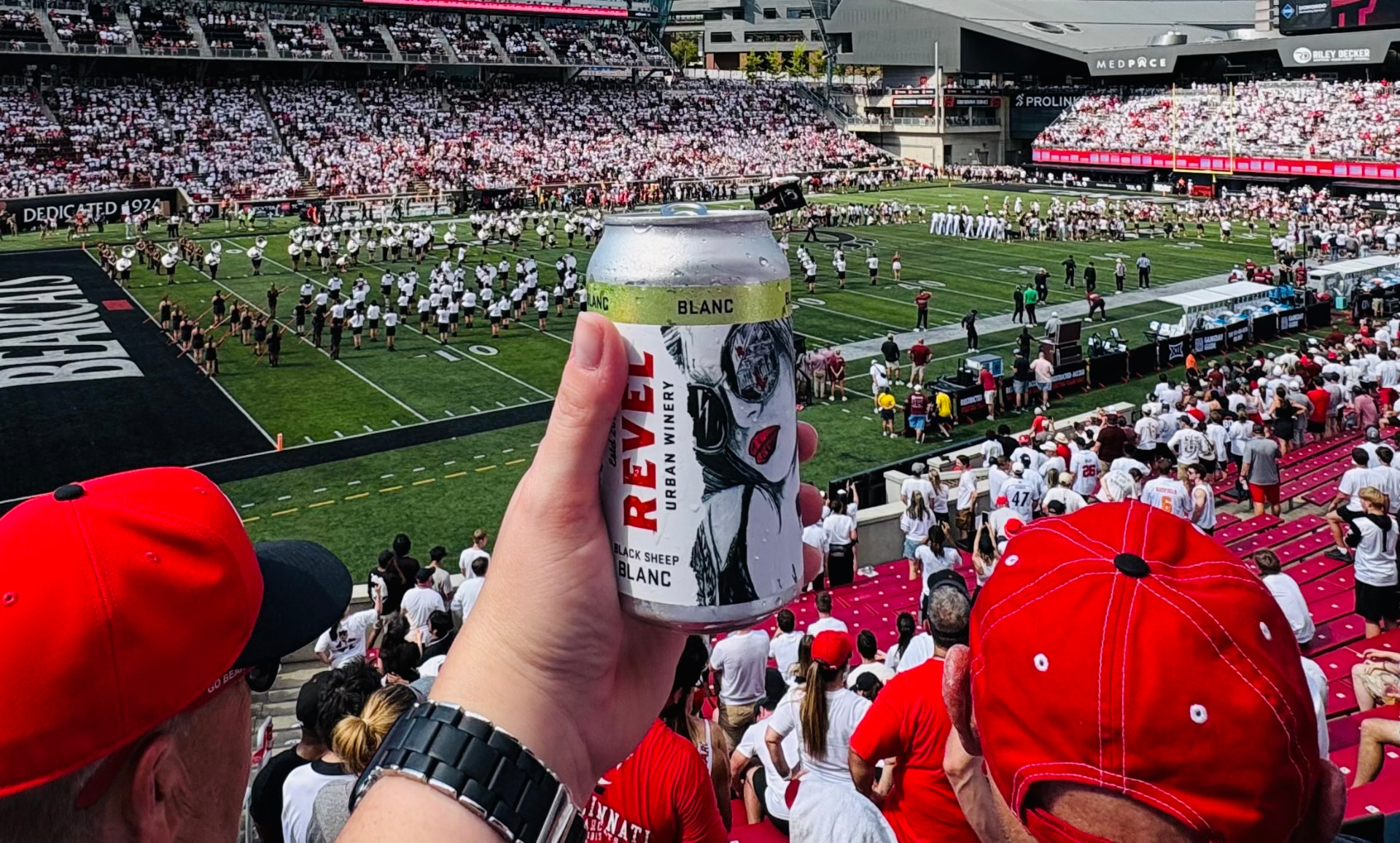 A can of Revel Black Sheep Blanc held up in the stands at a Cincinnati Bearcats football game